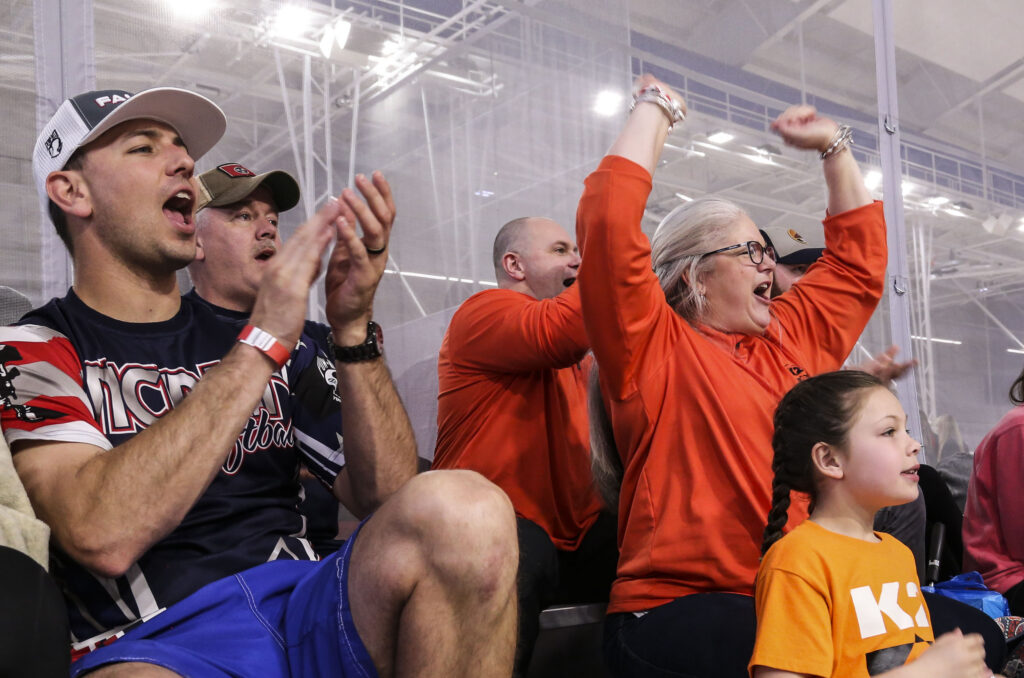 A diverse group of fans enthusiastically cheering and celebrating at a lively sporting event.