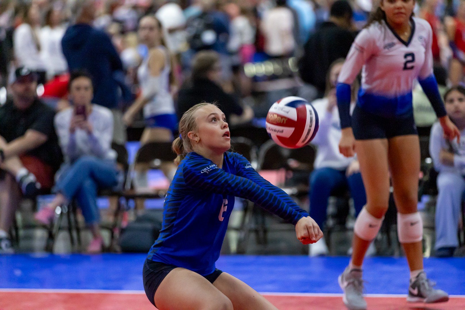 A volleyball player strikes the ball with her hand during a match, showcasing her athleticism and focus.