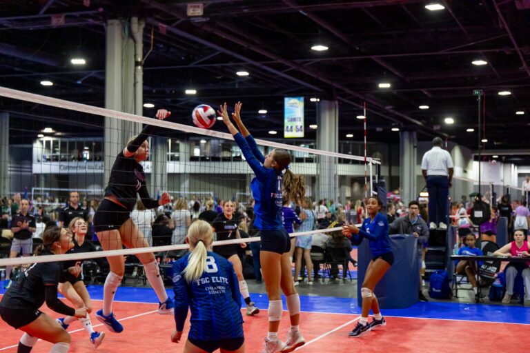 A volleyball player strikes the ball with her hand during a match, showcasing her athleticism and focus.
