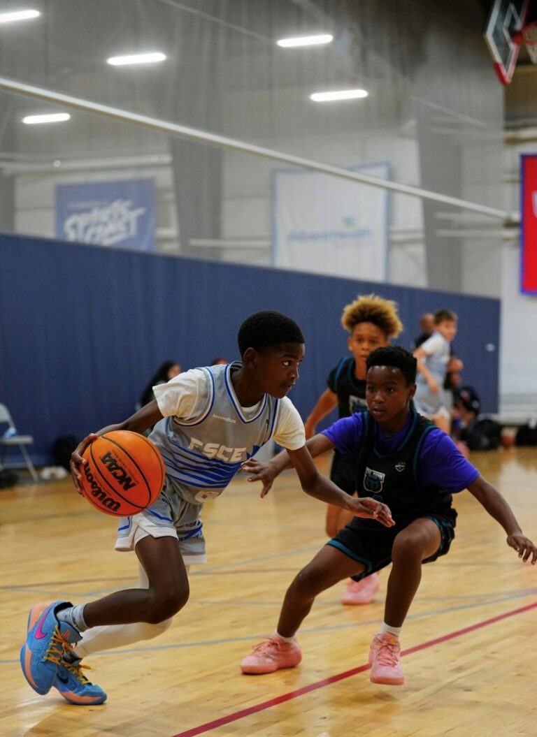 Two young boys engaged in a basketball game on a court, showcasing teamwork and athleticism.