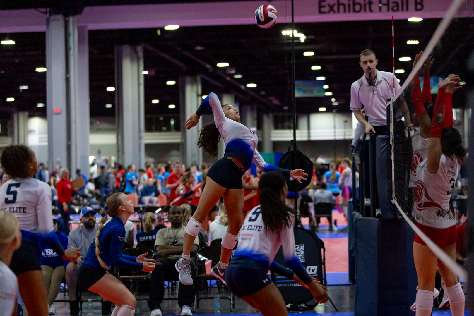 A volleyball player strikes the ball with her hand during a match, showcasing her athleticism and focus.