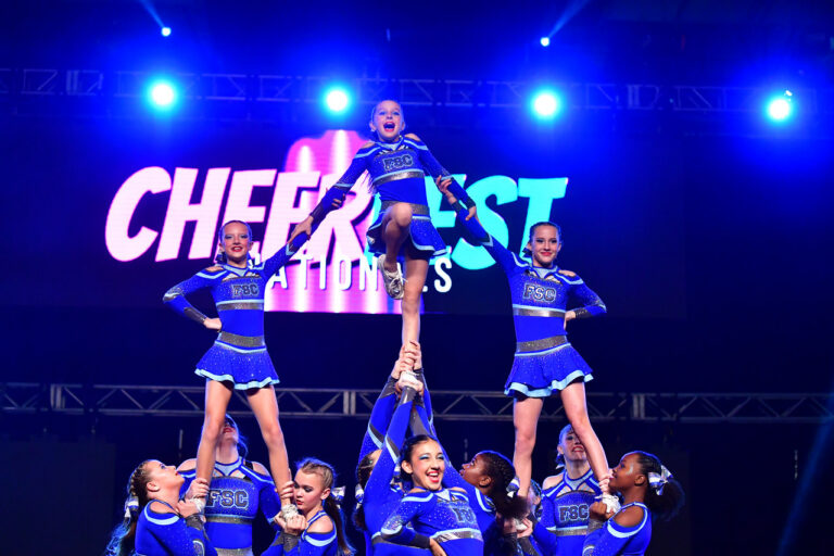 A group of cheerleaders in uniforms smiling and posing together for a team photo.