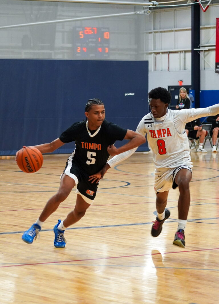 Two young men engaged in a basketball game on a court, showcasing athleticism and teamwork