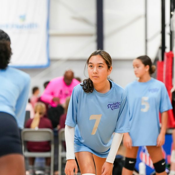Prep and Developmental Volleyball 28 A girl wearing a blue shirt is actively playing volleyball on a sandy court.