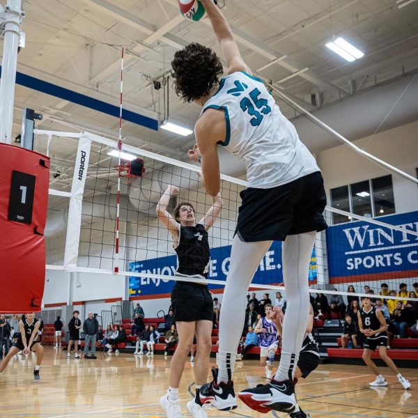 Prep and Developmental Volleyball 11 A man leaps into the air to strike a volleyball, showcasing athleticism and focus during a game
