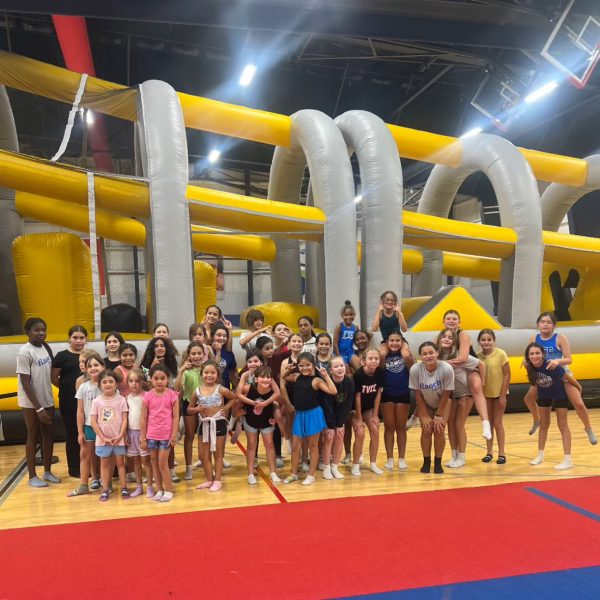 A group of children smiling and posing in front of a colorful inflatable obstacle course.
