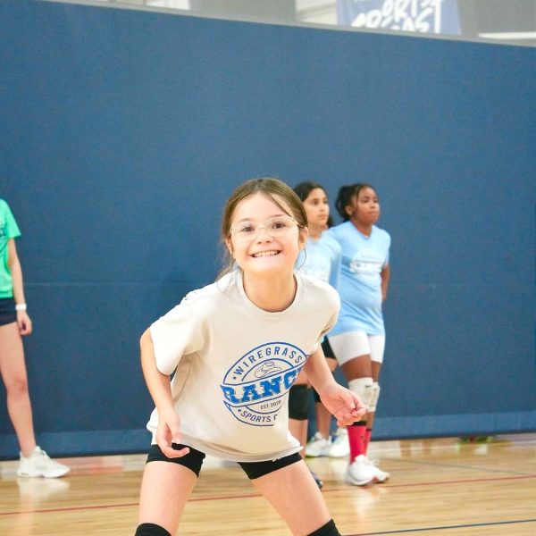 A young girl jumps to hit a volleyball on a court, showcasing her athleticism and enthusiasm for the game.