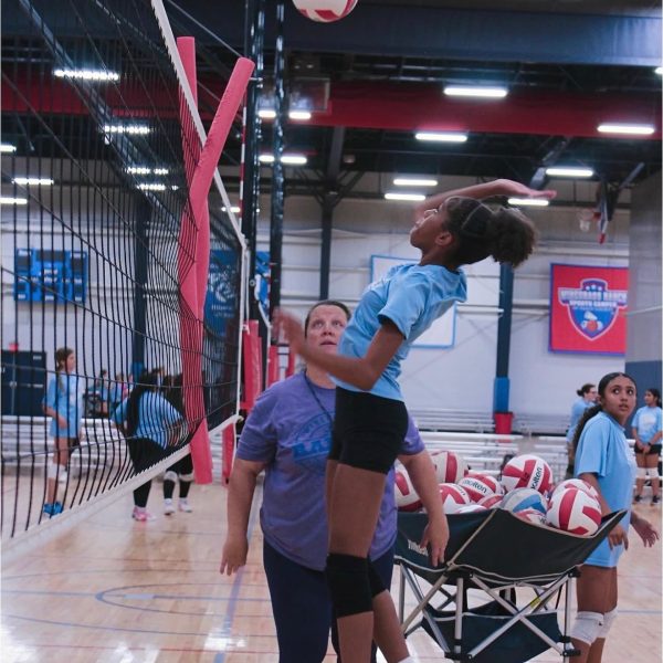 Prep and Developmental Volleyball 15 A girl leaps into the air to strike a volleyball, showcasing her athleticism and focus during a game.